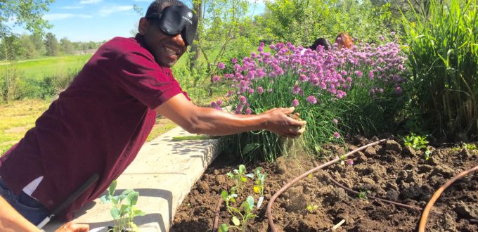 Man wearing sleepshades breaks clods of soil between his hands