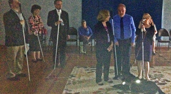 Three people stand at the front of a dimly-lit gym
