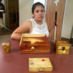Cindy stands behind her woodshop project. The large box is in the center with the smaller boxes arranged around it.