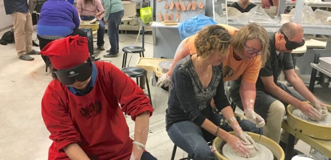 Six people work their clay on pottery wheels