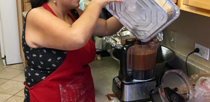 Young woman in sleepshades pours a sauce into a hotel pan