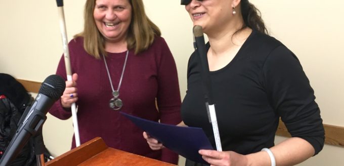 A woman presents a certificate to another woman, standing beside a podium.