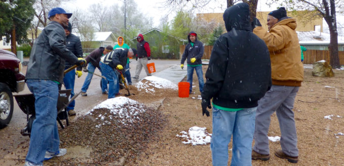 Workers with shoels, rakes and brooms in the snow and rain