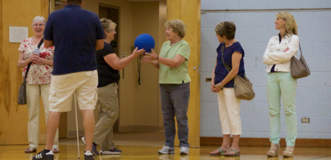 two women at the front of a group toss a a hefty goal ball back and forth