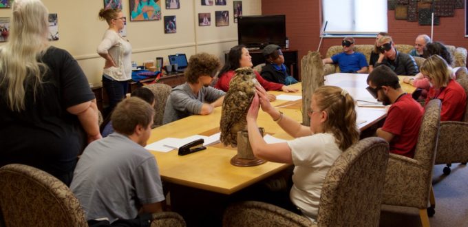 Group shot - The class listens to bird sounds while CG looks at a mount of a Great Horned Owl