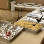 A Dozen Hotel Trays of food arrayed on three tables