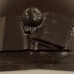 A black plastic sheet impressed with an apple atop one open and one closed book