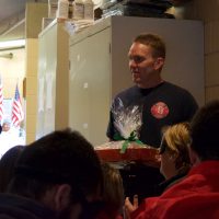 A Fire Fighter holds a tray of goodies presented by a group of CCB students