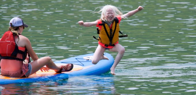 Cloe leaping from a paddle board during Confidence Camp