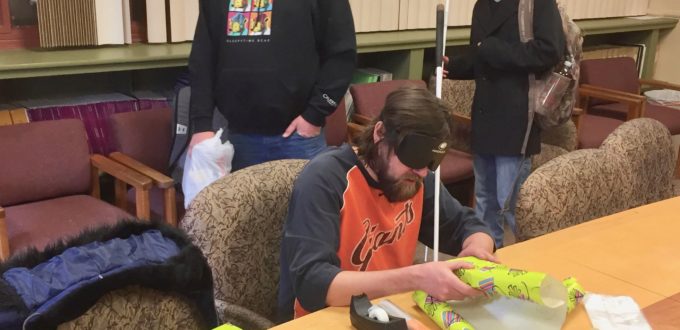 Graham wraps a gift with Chris Perez and Jackson walking in to do the same