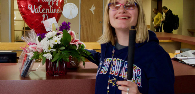 A smiling young woman holds a Happy Valentines Day Heart Shaped Balloon and Flower Arrangement
