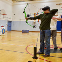 Lyne takes aim with her bow in Archery Class