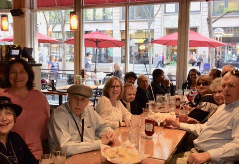 Seniors around a long table, laughing and talking with food