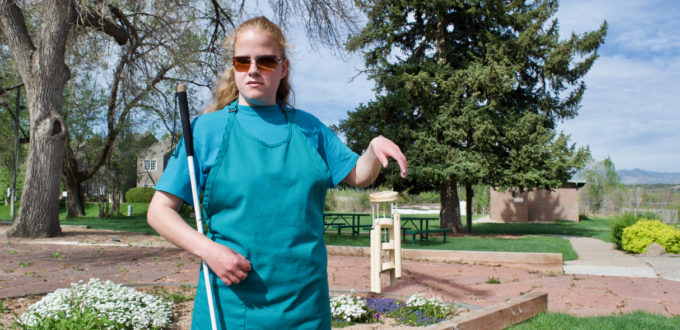 C.G. near the front garden holding up her wooden wind chime shop project