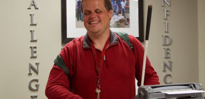 a smiling man types on the Brailler