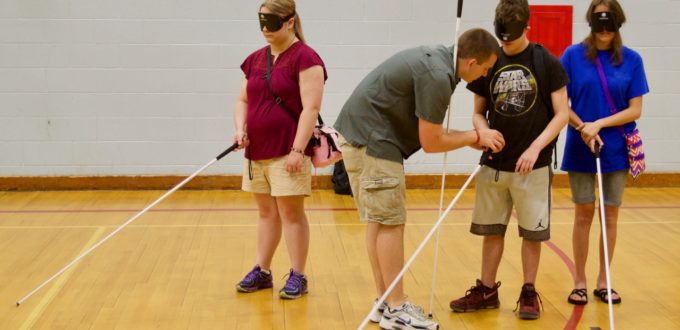 Garret works with 3 summer students in the Gym on holding their canes properly