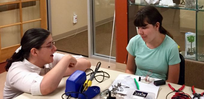 Jamie talks to Maddie while she works with a breadboard