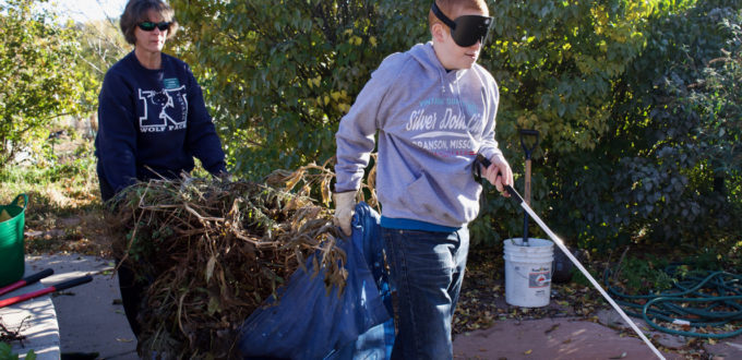 Tyler leads the way as he and Master Gardener Volunteer Barb P. carry a tarp loaded with stems and leaves pulled up from the garden