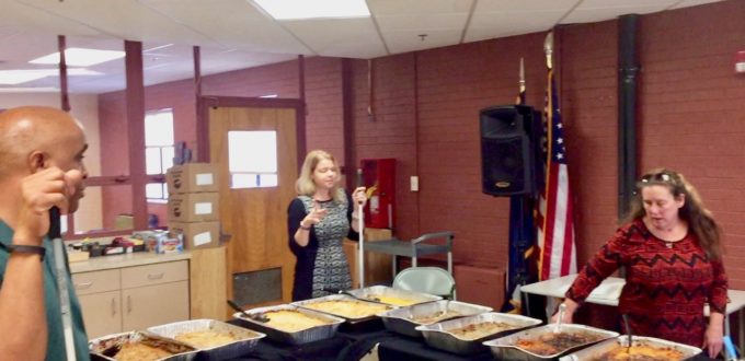 Dishon, Maureen and Vicki around the L shaped tables loaded with hotel tray full of food for Thanksgiving 2017s