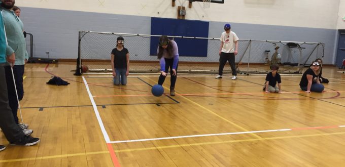 A student in sleepshades prepares to make a throw iwht the goal ball