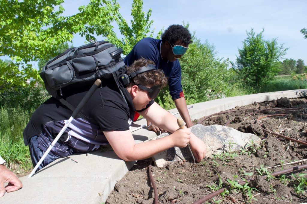 Tucker uses a weed digger to get right up next to a large rock