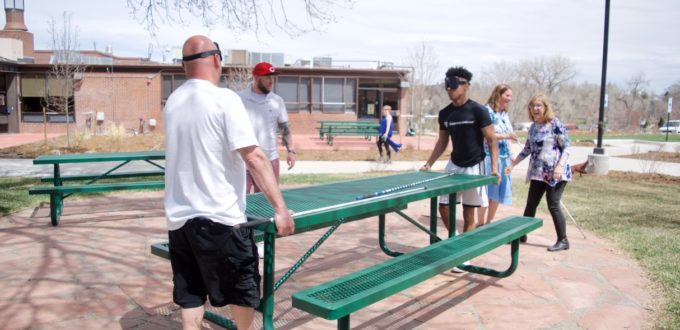 Omar, Charles and Kameron move picnic tables while Julie and Duncan figure out placement