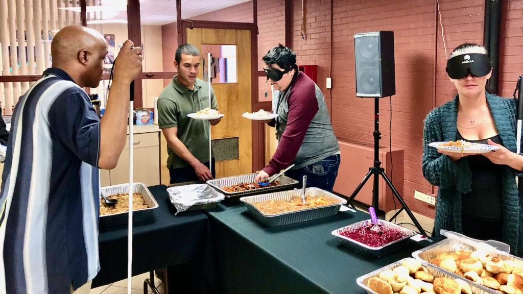 People filling Thanksgiving plates as they go around the extended serving line