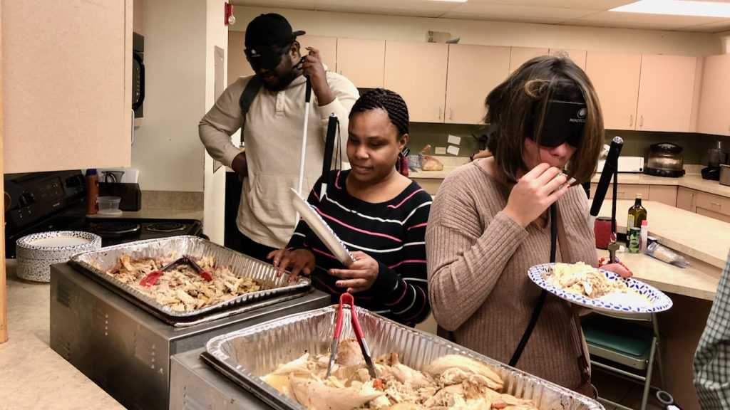 People filling Thanksgiving plates as they start at the beginning of the serving line