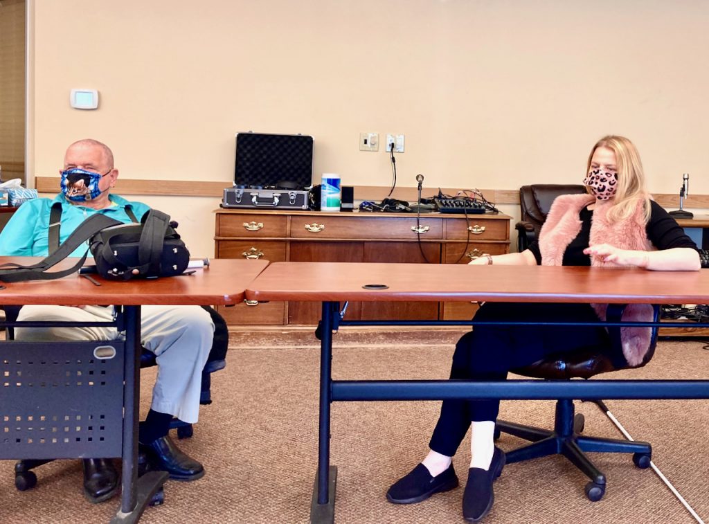 a man and woman wearing masks sit at nearby tables